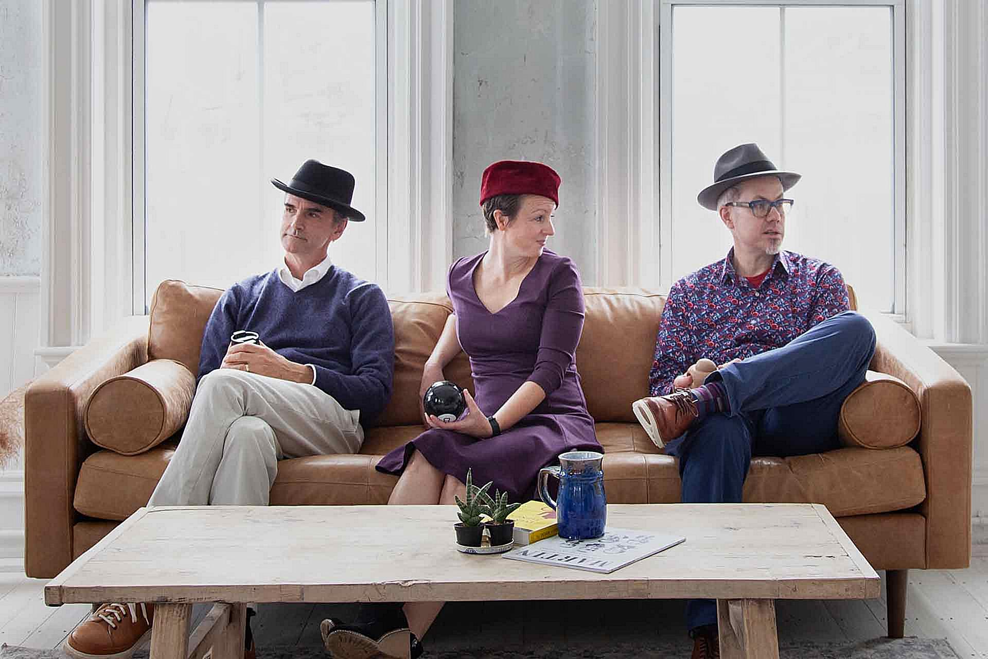 Ed, Annie, and Jim on a sofa wearing hats