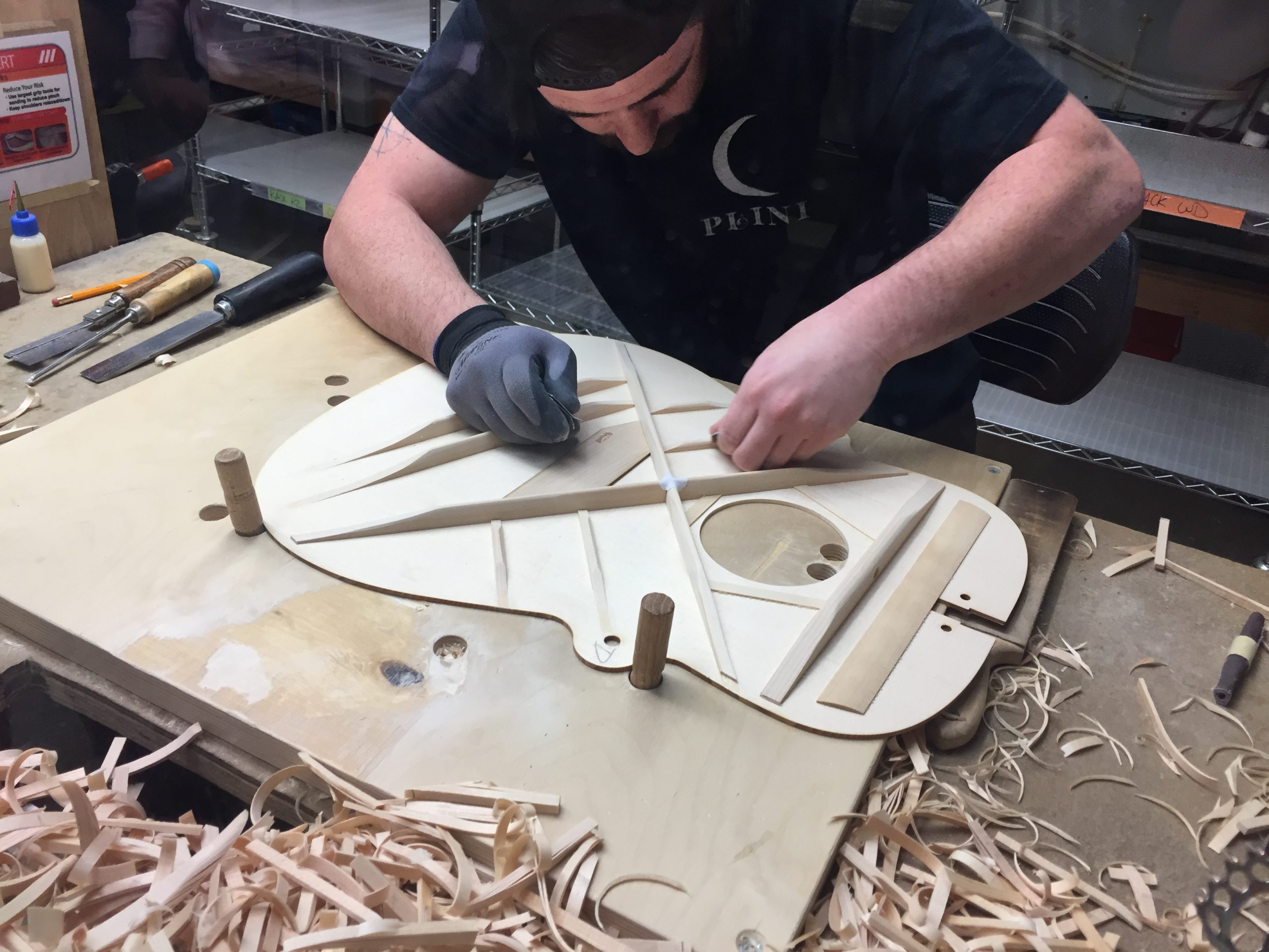 12. martin hand carving braces detail A luthier hand carving scalloped bracing on a guitar.
