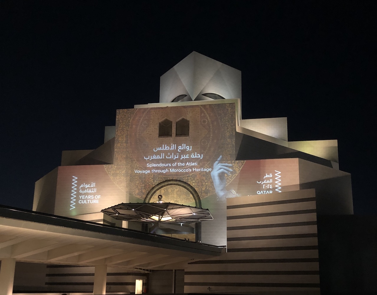 Facade mia Facade of Museum of Islamic Art at night with words projected onto it.