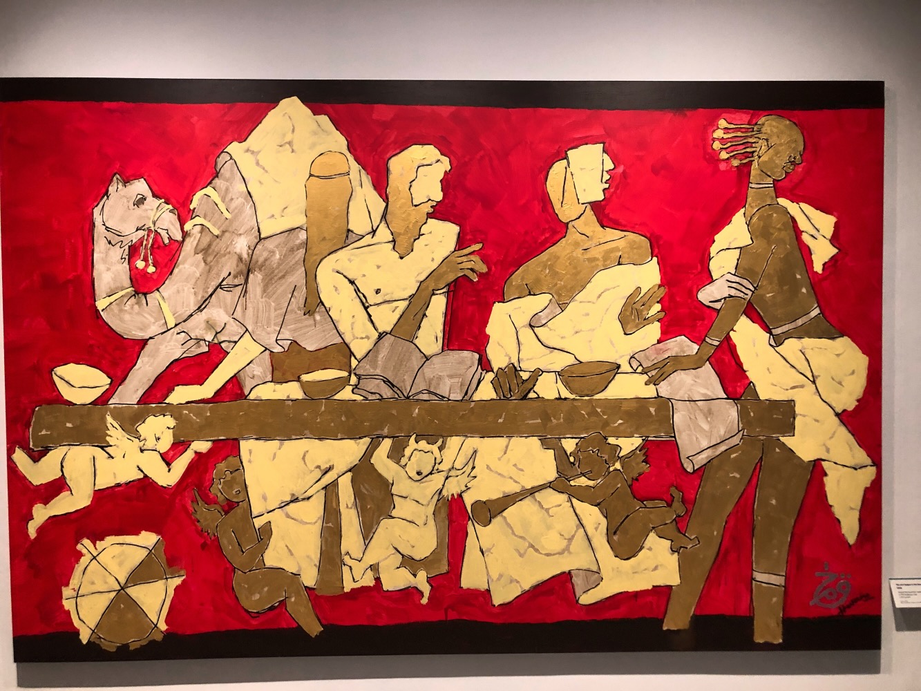 MF husain Painting in gold and red with people, cherubs, and a camel around a table.