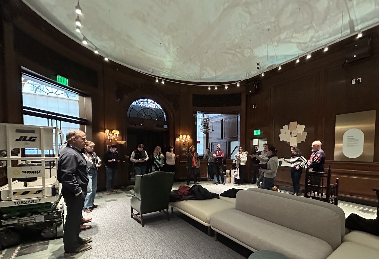 team final walk thru Old library building with team meeting, lift in the background, work in progress.